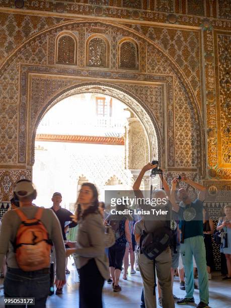 Tourists admire the ceiling of the Ambassadors Hall , also known as the Throne Room in the Mudejar palace of the Alcazar in Seville, a royal palace...