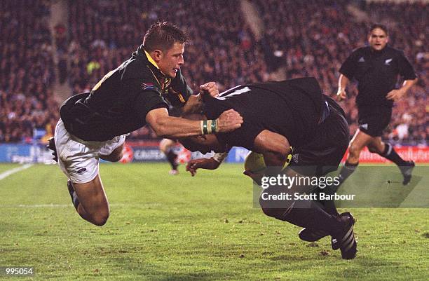 Jonah Lomu of New Zealand is tackled by Bob Skinstad of South Africa during the Tri Nations match between New Zealand and South Africa played at Eden...