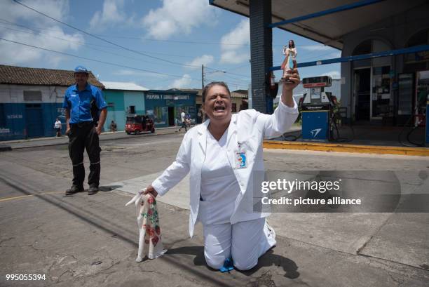 July 2018, Nicaragua, Diriamba: A woman kneels on the ground before the arrival of a Catholic mission. The archbishop of Managua, Cardinal Brenes,...