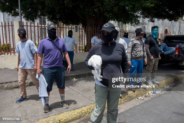 July 2018, Nicaragua, Diriamba: Several masked people stand guard outside a church. While a Catholic mission tried to get into the church, where at...