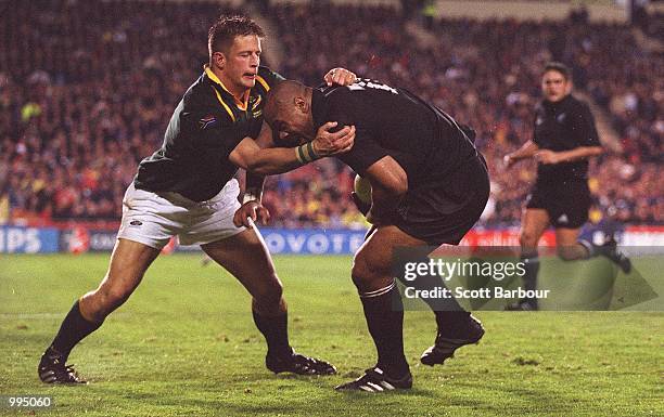 Jonah Lomu of New Zealand is tackled by Bob Skinstad of South Africa during the Tri Nations match between New Zealand and South Africa played at Eden...