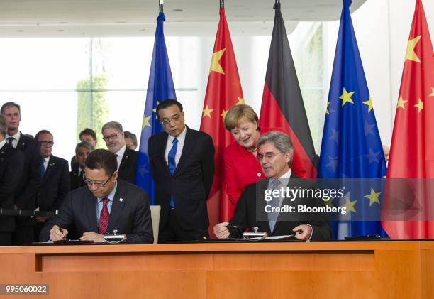 Qian Zhimin, president of China National Nuclear Corp., left, and Joe Kaeser, chief executive officer of Siemens AG, right, sign documents as Li...