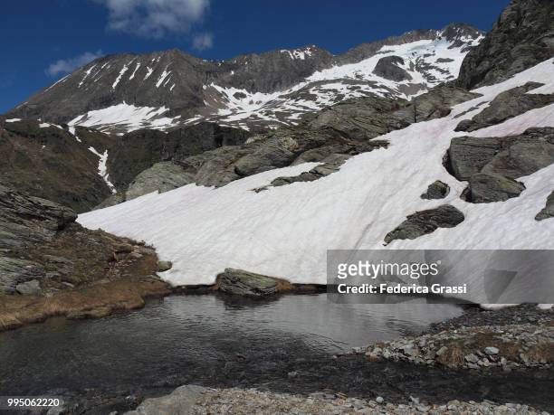 small pond and patches of snow in the high formazza valley - lepontinische alpen stock-fotos und bilder