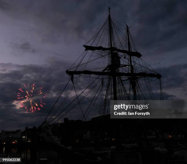 Fireworks explode in the evening sky behind the Tall Ship Atyla as it is moored in Whitby Harbour during the second day of the Whitby Captain Cook...