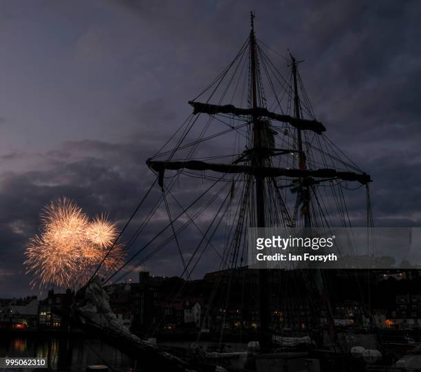 Fireworks explode in the evening sky behind the Tall Ship Atyla as it is moored in Whitby Harbour during the second day of the Whitby Captain Cook...