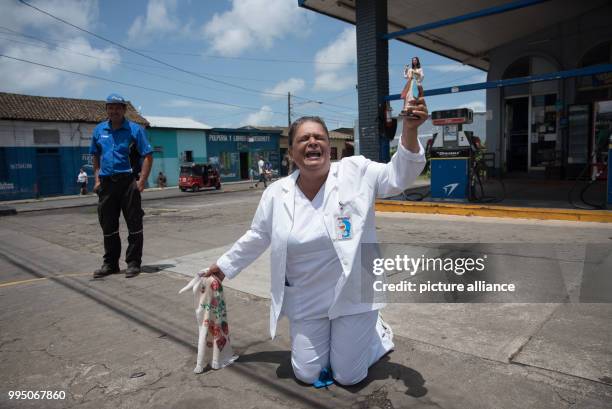 July 2018, Nicaragua, Diriamba: A woman kneels on the ground before the arrival of a Catholic mission. The archbishop of Managua, Cardinal Brenes,...