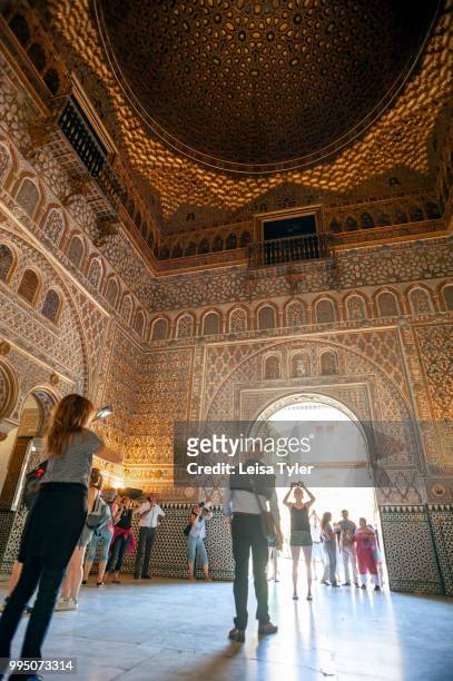 Tourists in the Ambassadors Hall , also known as the Throne Room in the Mudejar palace of the Alcazar in Seville, a royal palace built for the...