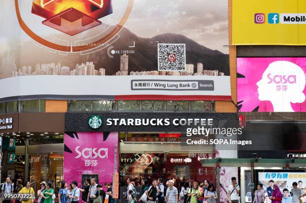 Pedestrians walk past numerous advertisements in Hong Kong.