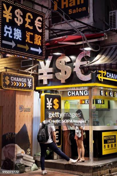 Tourists exchanging currency at a money change counter and Western Union branch in Mong Kok, Hong Kong.