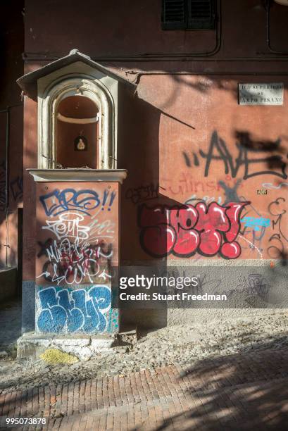 Street shrine and graffiti in a back street of mediaeval Genoa, Italy.