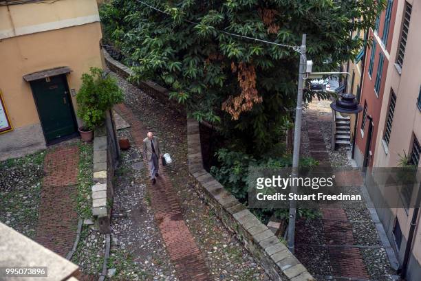 An elderly man walks through a residential district of the mediaeval centre of Genoa, Italy.