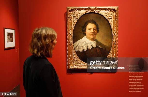 Member of staff looking at the oil painting "Willem Burchgraeff" from the Rembrandt Harmensz van Rijn workshop, at the exhibition "The Birth of the...