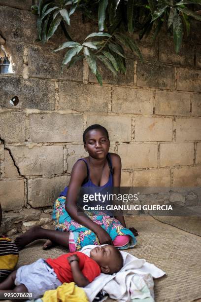 Emma sits with her son in her house backyard on July 5, 2018 in Nacala, Nampula Province, Mozambique. - The United Nations Fund for Population...