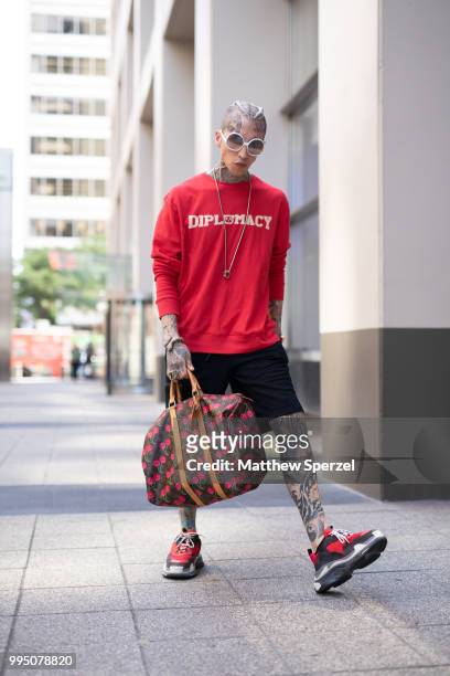 Chris Lavish is seen on the street attending Men's New York Fashion Week wearing a Diplomacy shirt and shorts, a Louis Vuitton bag, Balenciaga...