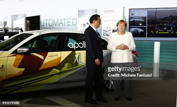 German Chancellor Angela Merkel and Chinese Premier Li Keqiang pose in front of a BMW electric car as they attend an event to present a project on...