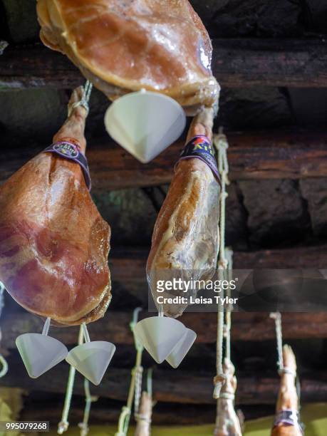 Jamon serrano hang from the ceiling in Bodega El Atroje, a small bar in the town of Capileira, Spain. Grazing on acorns in the surrounding mountains,...
