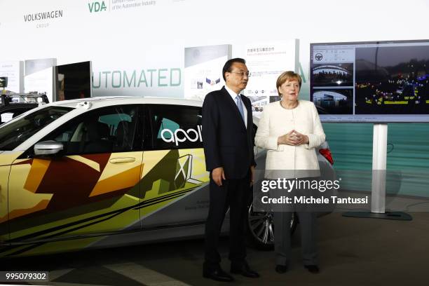 German Chancellor Angela Merkel and Chinese Premier Li Keqiang pose in front of a BMW electric car as they attend an event to present a project on...