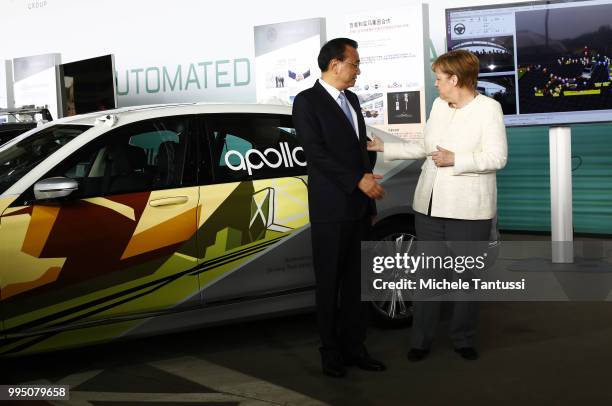 German Chancellor Angela Merkel and Chinese Premier Li Keqiang pose in front of a BMW electric car as they attend an event to present a project on...