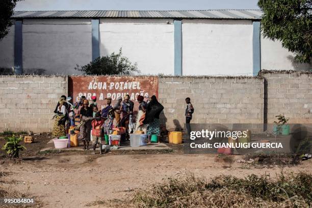 Women and children draw water from a public water point on the main road on July 5, 2018 in Nacala, Mozambique.