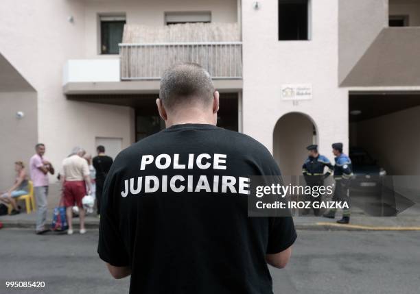 Policemen stand in front of a building after five people including one child were killed when a fire tore through an apartment in Pau, southwestern...
