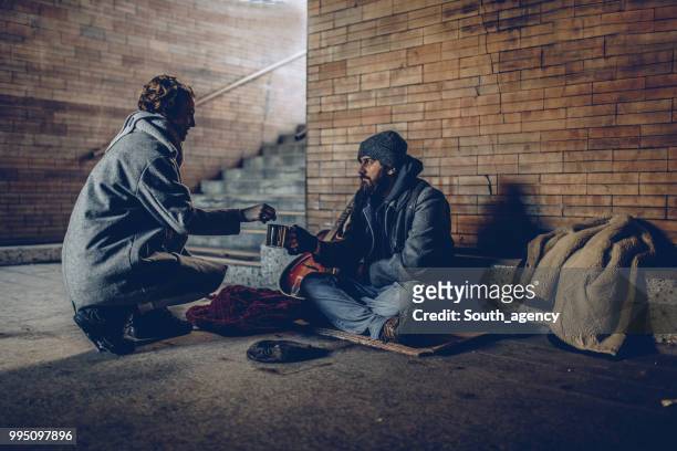 woman giving money to beggar man - begging social issue stock pictures, royalty-free photos & images