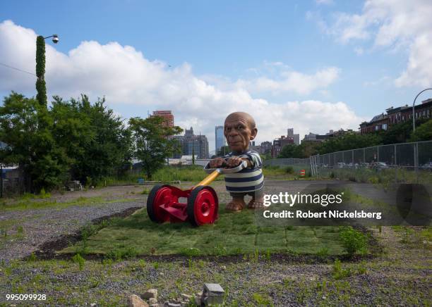 Foot sculpture of Spanish artist Pablo Picasso mowing a lawn, The Spanish Gardener by Elliott Arkin, stands on ground near the Red Hook Container...