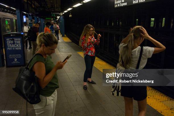 Passengers wait for a subway July 5, 2018 at the Union Square Station in New York. The New York subway system faces a deteriorating infrastructure...