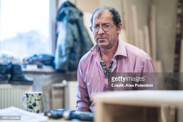 the 60-years-old senior, sashman, taking a break and resting with the cup of tea at the small wood manufacture - alex potemkin or krakozawr stock pictures, royalty-free photos & images