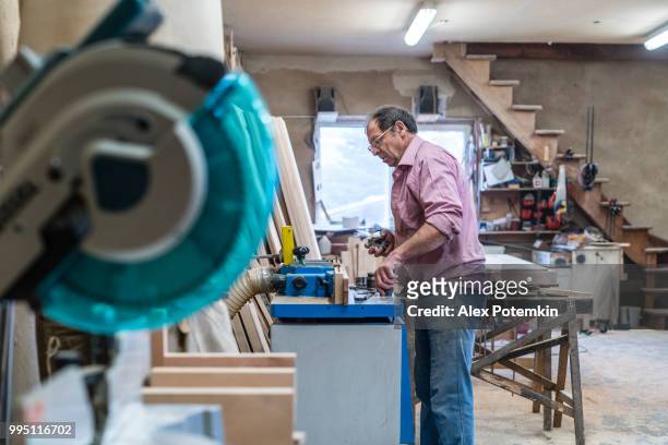 der senior 60 jahre alten mann, tischler und sashman, handwerker, arbeiten mit der industriellen fräsmaschine bei der kleinen holz-fabrik - alex potemkin or krakozawr stock-fotos und bilder