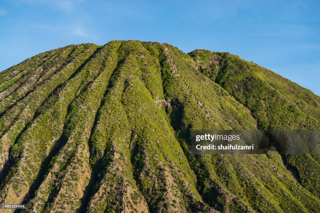 Mount Batok (2,470m), though lying adjacent to Mount Bromo. With a perfect triangular mountain top, rising from a sea of volcanic ash surrounding the Mount Bromo caldera. East Java of Indonesia.