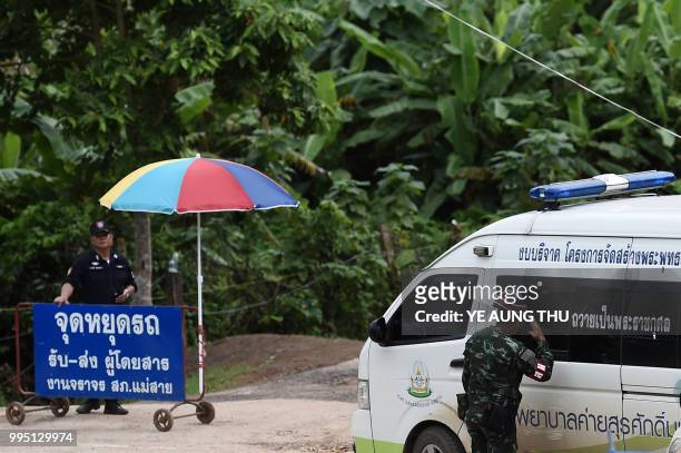 Thai military police salutes an ambulance leaving from the Tham Luang cave area as the operations continue for those still trapped inside the cave in...