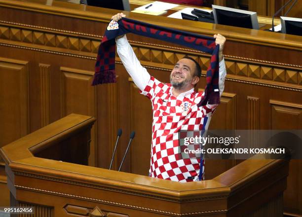 Ukraine football federation chief and lawmaker Andriy Pavelko, wearing T-shirt of the Croation football team, holds a scarf with the sign "Croatia"...