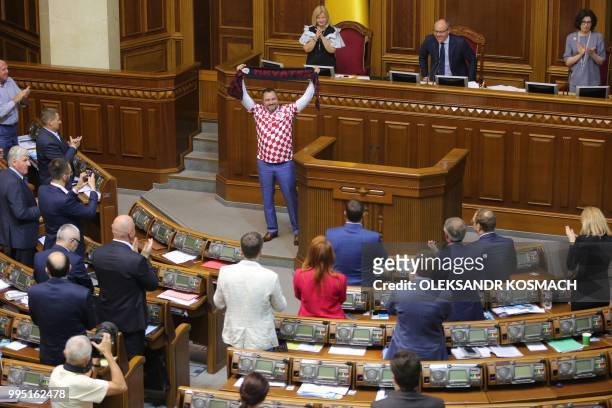 Ukraine football federation chief and lawmaker Andriy Pavelko, wearing T-shirt of the Croation football team, holds a scarf with the sign "Croatia"...