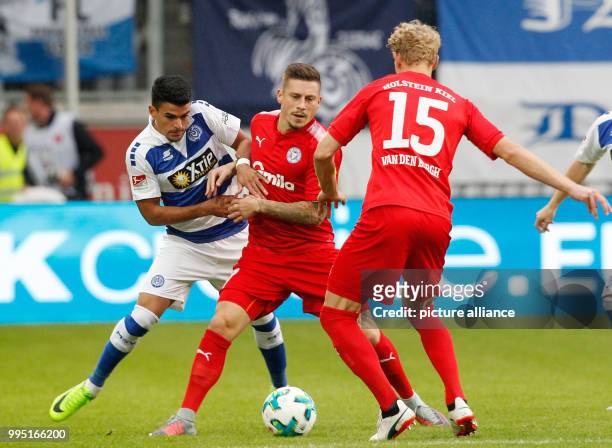 Duisburg's Enis Hajri and Kiel's Johannes van den Bergh and Steven Lewerenz vie for the ball during the German Second Bundesliga soccer match between...