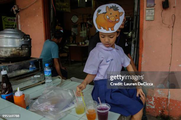 Young Thai girl wears a wild boar hat as she waits for the boys to be delivered safety to Chiangrai Prachanukroh Hospital on July 10, 2018 in Chiang...