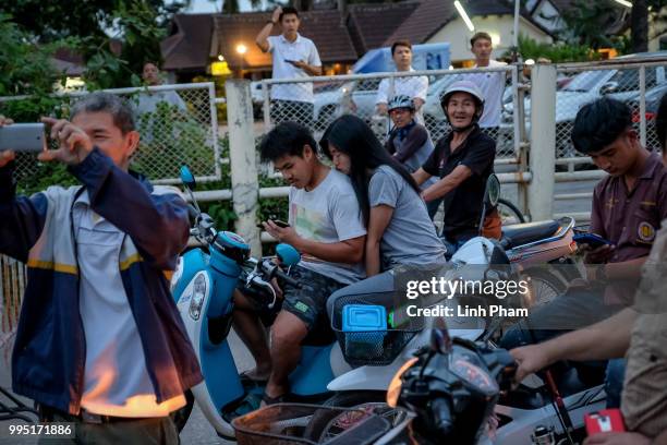 Onlookers watch and cheer as ambulances transport the 10th rescued schoolboy from a helipad nearby to Chiangrai Prachanukroh Hospital on July 10,...