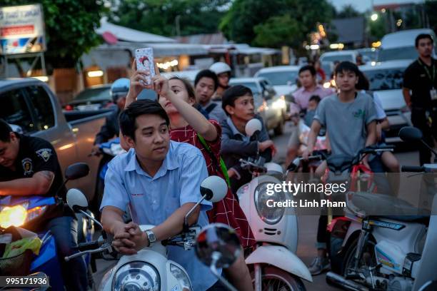 Onlookers watch and cheer as ambulances transport the 10th rescued schoolboy from a helipad nearby to Chiangrai Prachanukroh Hospital on July 10,...