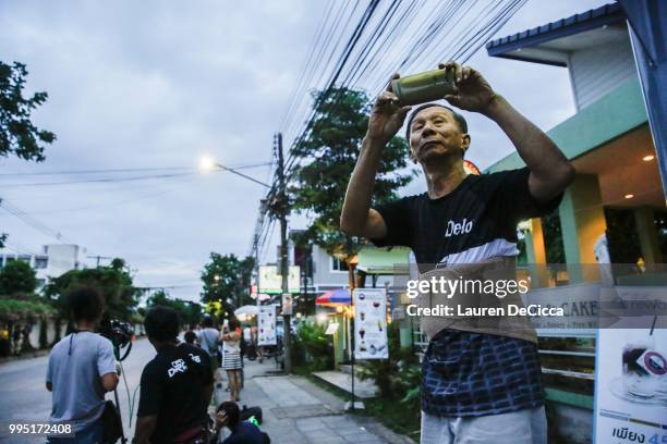 Man films ambulances with a smart phone as it transports some of the rescued schoolboys from a helipad to Chiangrai Prachanukroh Hospital on July 10,...