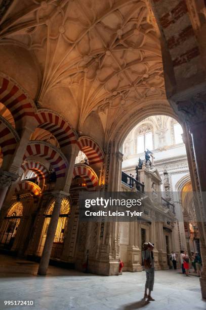 Islamic arches with a catholic cathedral in the background at the Cordoba Mezquita in Spain. Built as a mosque in 785, then later converted into a...