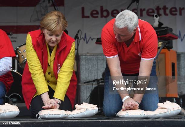 German chancellor Angela Merkel sits atop a resuscitation doll next to Prof. Dr. Med. Klaus Hahnenkamp on stage in Greifswald, Germany, 23 September...
