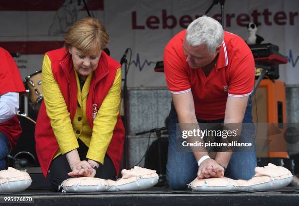 Dpatop - German chancellor Angela Merkel sits atop a resuscitation doll next to Prof. Klaus Hahnenkamp on stage during the closing event of the...