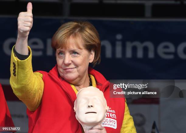 German chancellor Angela Merkel gives a thumbs up as she stands on stage during the closing event of the project week "resuscitation" of the...