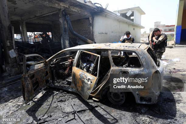 People inspect the scene near a wrecked car after a suicide bombing in Jalalabad in eastern Nanganhar province of Afghanistan on July 10, 2018....