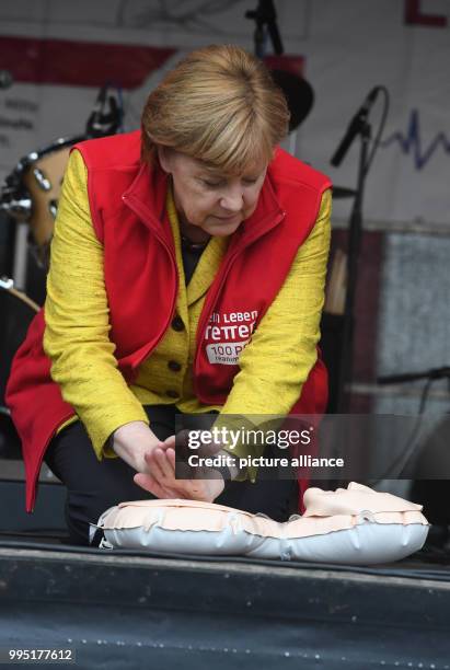 German chancellor Angela Merkel sits atop a resuscitation doll on stage during the closing event of the project week "resuscitation" of the...