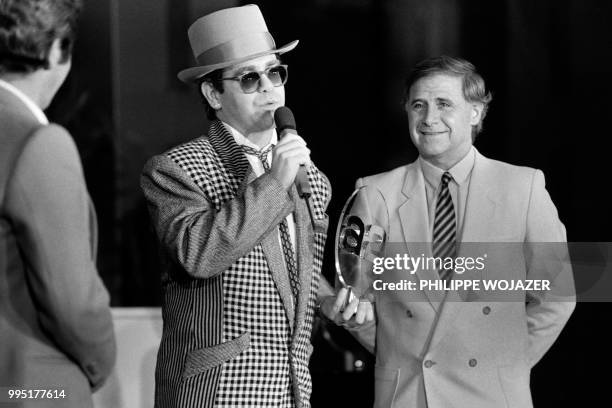 Photo taken on December 17, 1984 in Paris shows English singer Elton John and French coach of the national team Michel Hidalgo during the awarding...