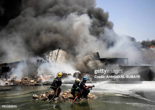 Iraqi firefighters attempt to put out a fire that broke out due to extreme summer temperatures in a warehouses near Palestine Street in the capital...