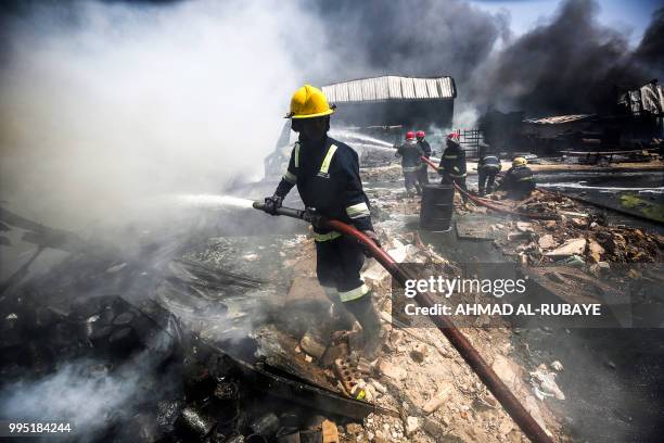 Iraqi firefighters attempt to put out a fire that broke out due to extreme summer temperatures in a warehouses near Palestine Street in the capital...