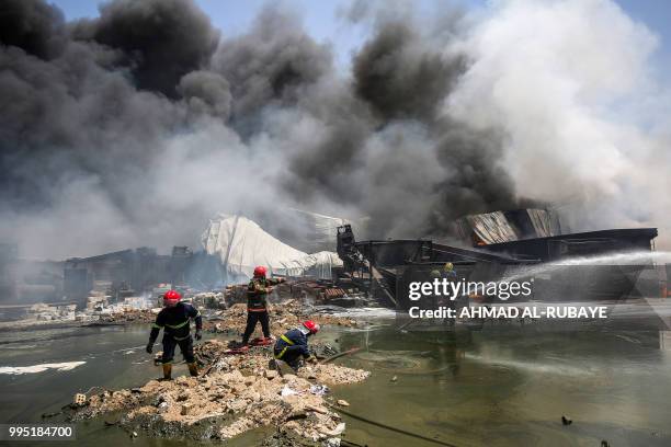 Iraqi firefighters attempt to put out a fire that broke out due to extreme summer temperatures in a warehouses near Palestine Street in the capital...