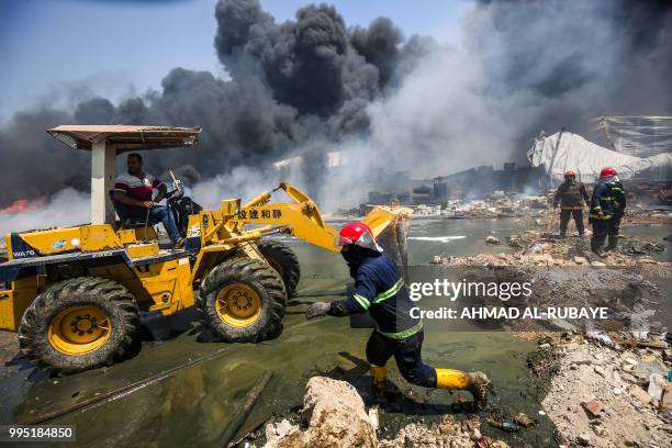 Iraqi firefighters attempt to put out a fire that broke out due to extreme summer temperatures in a warehouses near Palestine Street in the capital...