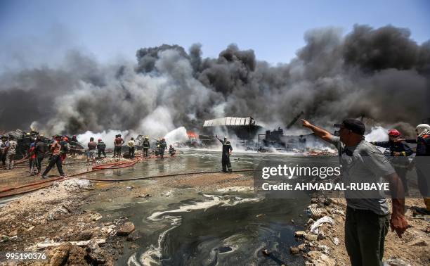 Iraqi firefighters attempt to put out a fire that broke out due to extreme summer temperatures in a warehouses near Palestine Street in the capital...